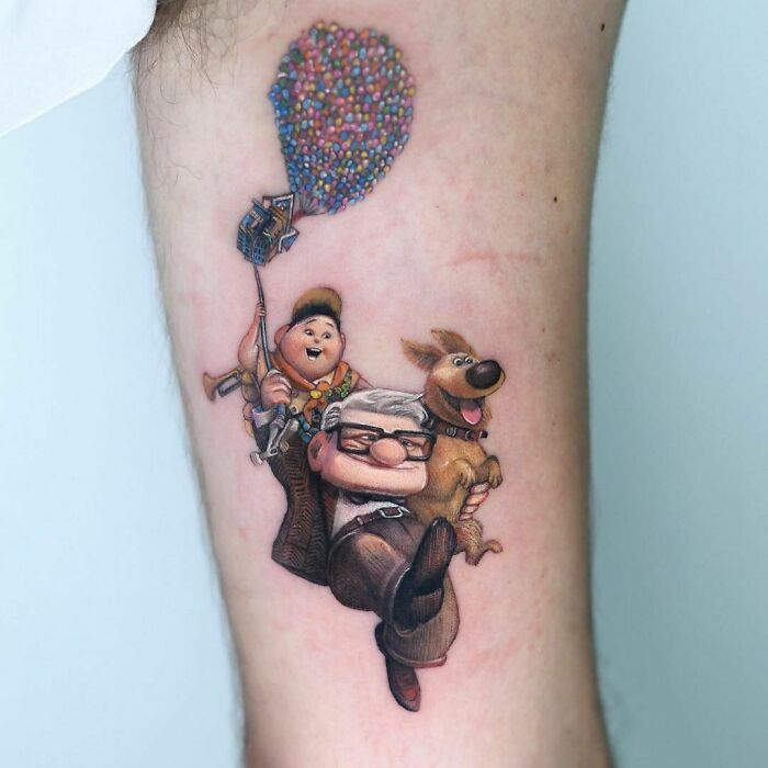 Cartoon tattoo featuring characters from Up with colorful balloons on a person's leg, showcasing nostalgia.