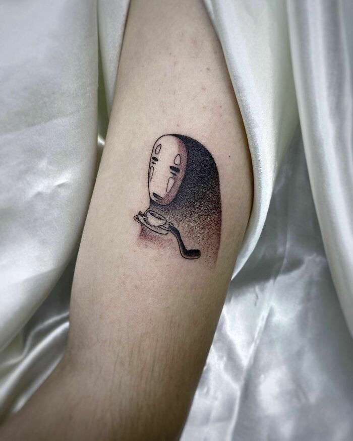 Cartoon tattoo of a masked character on an arm, with a nostalgic childhood theme.