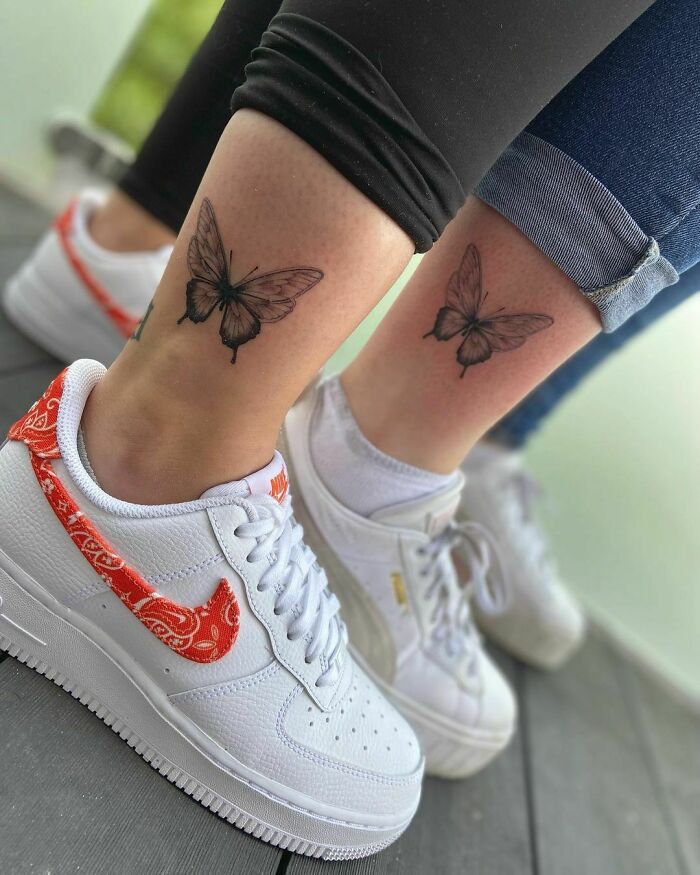 Two friends with matching butterfly tattoos on their ankles, wearing white sneakers, symbolizing BFF friendship tattoos.
