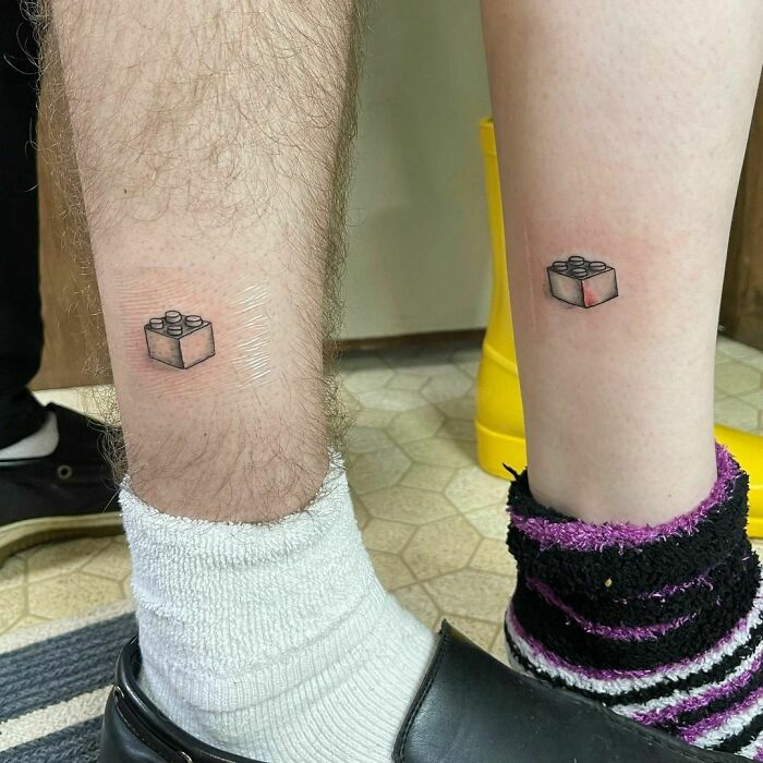 Small, simple brother and sister tattoos featuring matching Lego brick designs on calves.