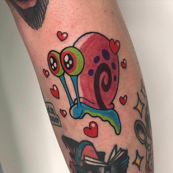 Cartoon tattoo of a colorful snail with hearts on an arm.