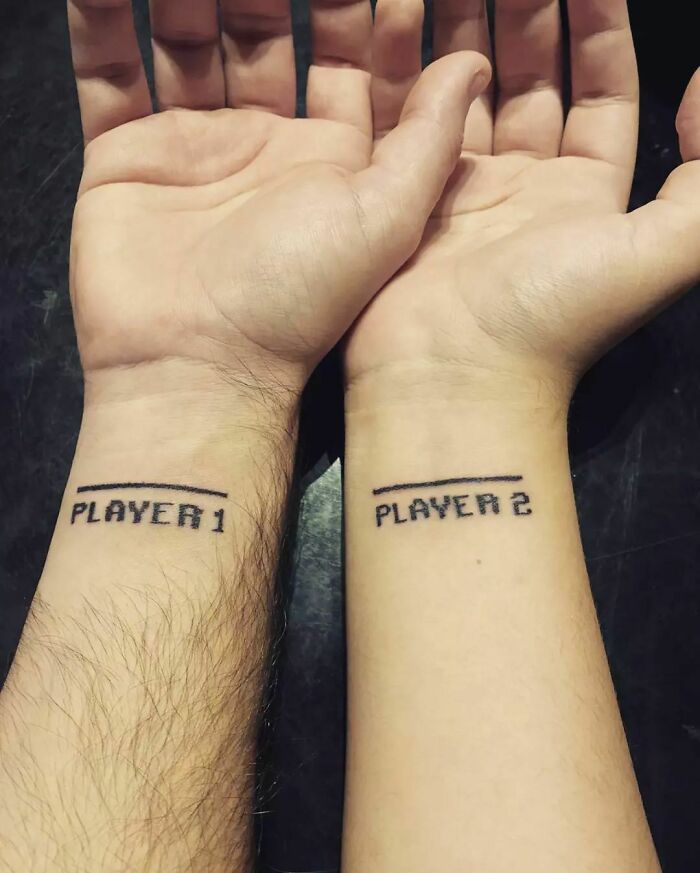Brother and sister wrist tattoos reading "Player 1" and "Player 2," symbolizing sibling bond.