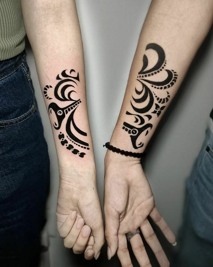 Brother and sister tattoos on forearms featuring black tribal designs symbolizing unity and connection.