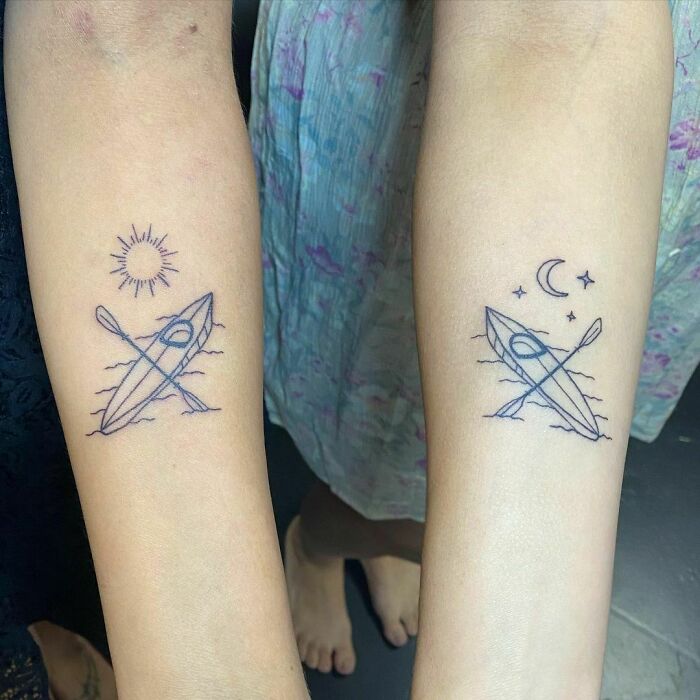 Matching BFF tattoos featuring kayaks and oars under sun and moon symbols on forearms.