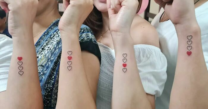 Four arms with matching heart tattoos, representing simple brother and sister tattoo ideas.
