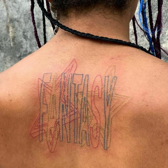 "Back tattoo with colorful 'Fantasy' word design, featuring layered outlines in star shapes."