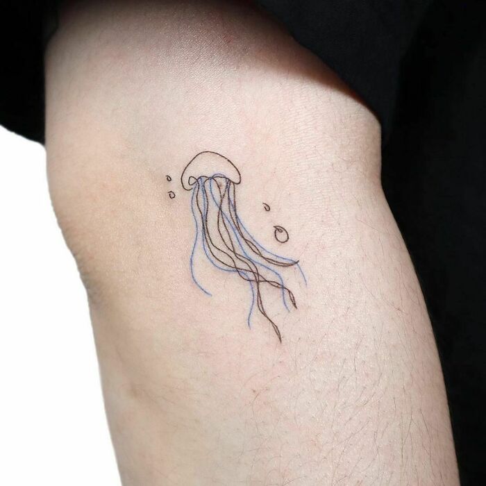 Single-line tattoo of a jellyfish on forearm, showcasing minimalist artistry.