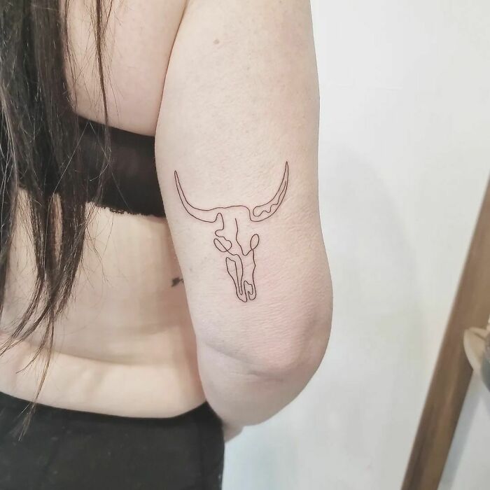 Minimalist line tattoo of a bull skull on an arm, showcasing unique ink art for minimalism enthusiasts.