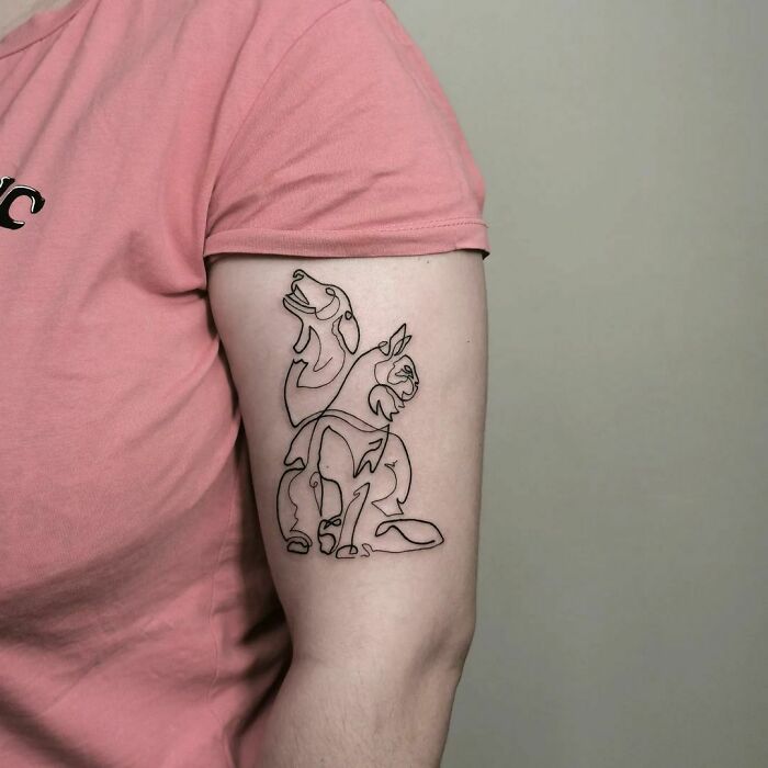 Single-line tattoo depicting abstract animals on a person's arm in a pink shirt.