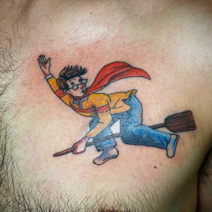 Tattoo of a wizard on a broomstick, featuring a red cape and glasses, inspired by Harry Potter themes.