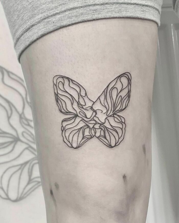 Line tattoo of a minimalist butterfly design on an arm.