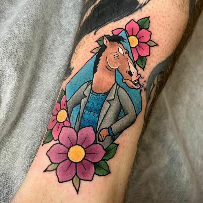 Cartoon tattoo featuring a horse character in a blazer surrounded by colorful flowers, inspired by animated shows.