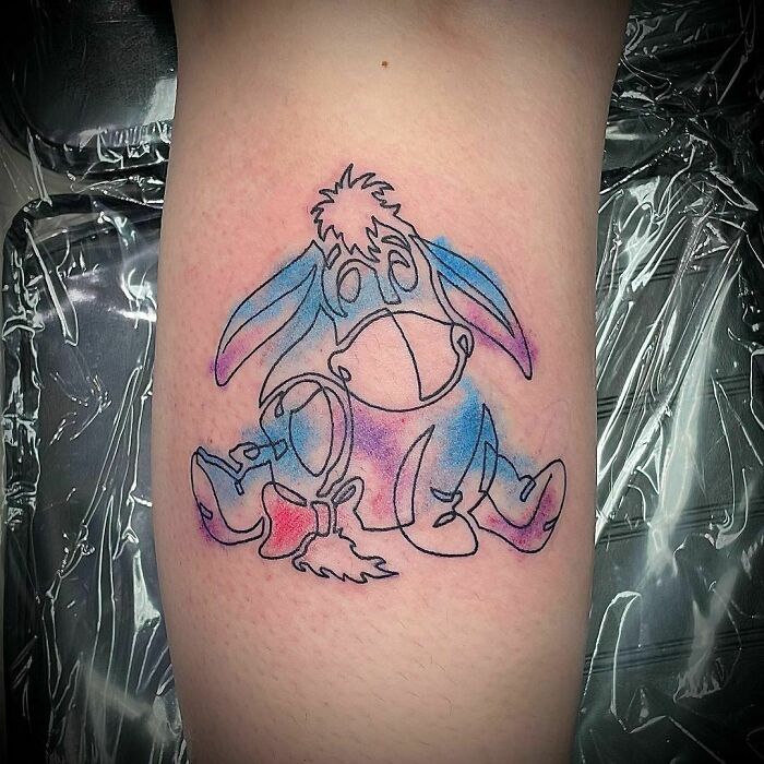 Tattoo of a cartoon character in pastel colors on an arm, evoking childhood favorites.