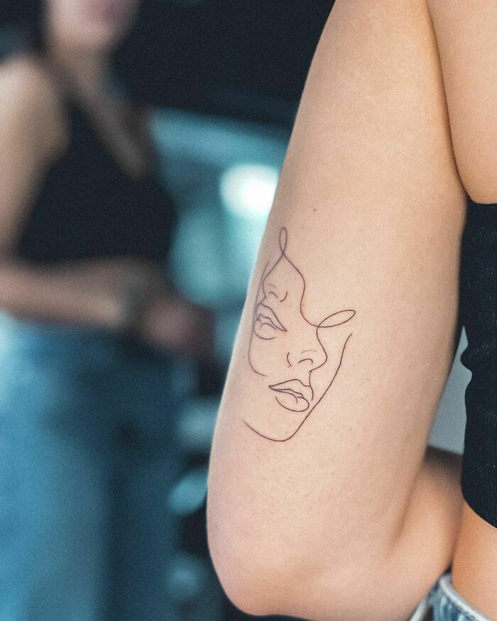Minimalist line tattoo of a face on an arm, representing unique tattoo ideas for minimalism enthusiasts.