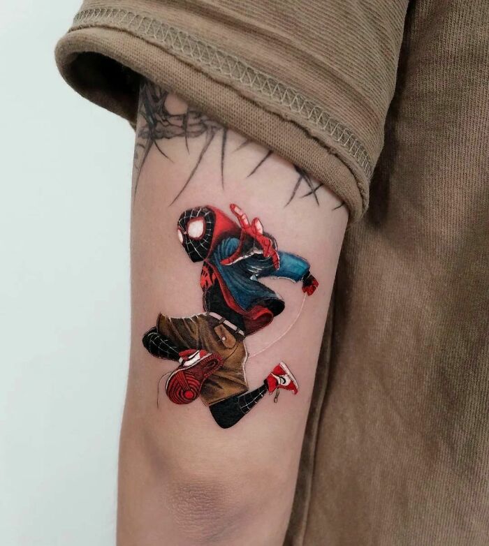 Marvel tattoo featuring Spider-Man on a person's upper arm, showcasing vibrant colors and intricate design.