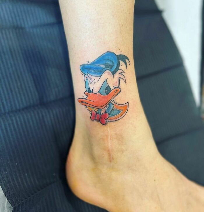 Colorful cartoon tattoo of a classic animated character on a person's ankle.
