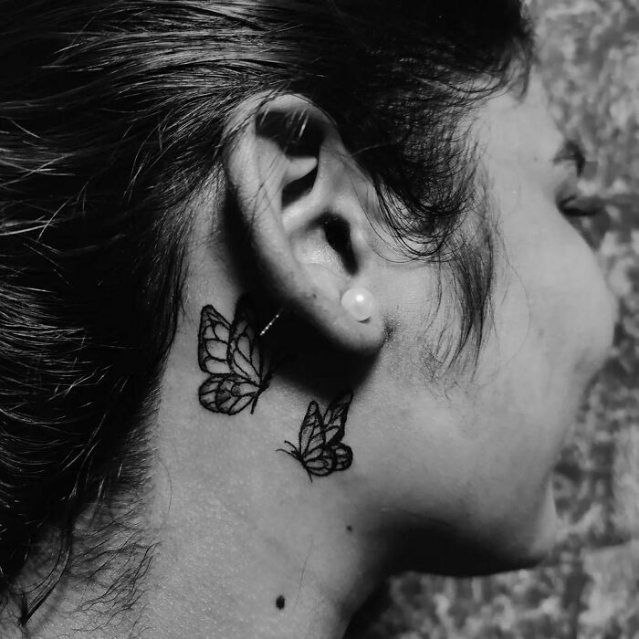 Butterfly ear tattoo design, subtle ink art behind ear on female.