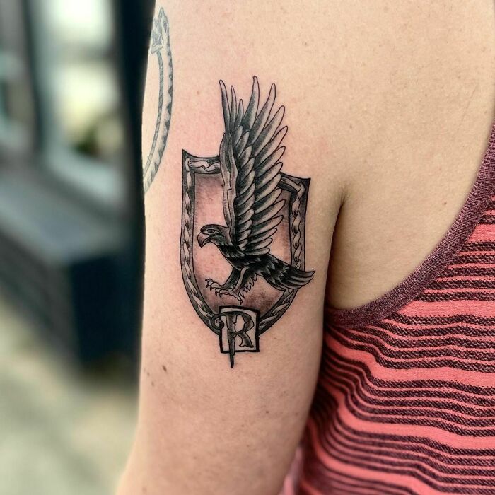 Harry Potter tattoo with a raven design on a person's upper arm, showcasing wizarding world fandom.