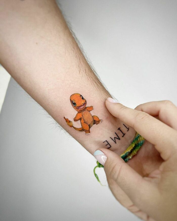 Cartoon tattoo of a small orange creature on an arm, evoking childhood favorites.