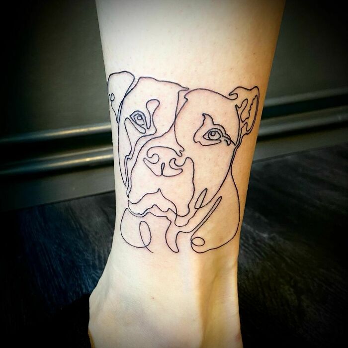 Fine-line single-line tattoo of a dog on the back of someone's leg.