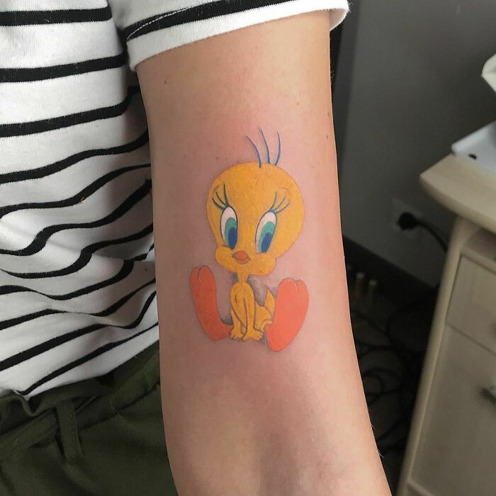 Cartoon tattoo of a yellow bird character on a person's forearm, evoking childhood favorites.