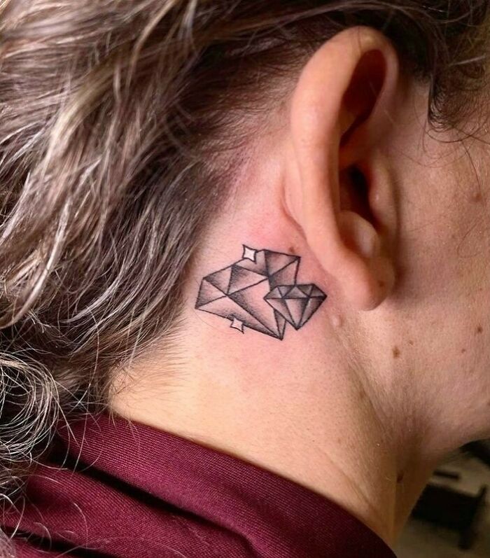 Geometric diamond ear tattoo on a person, using bold black lines for an artistic effect.