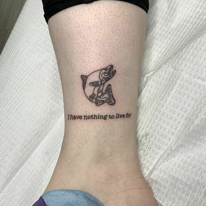 Single-line tattoo of fish with text "I have nothing to live for" on a person's leg.
