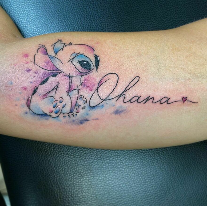 Watercolor tattoo of a cute creature with "Ohana" script and heart, blending soft pink and blue hues.