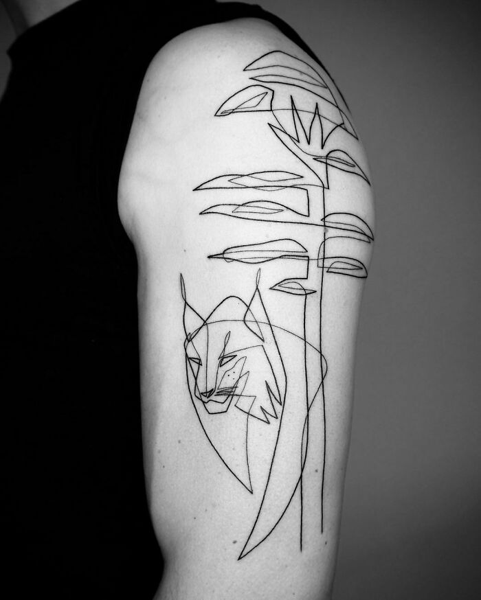 Single-line tattoo of a stylized wolf and abstract plant design on upper arm, showcasing intricate artistry.