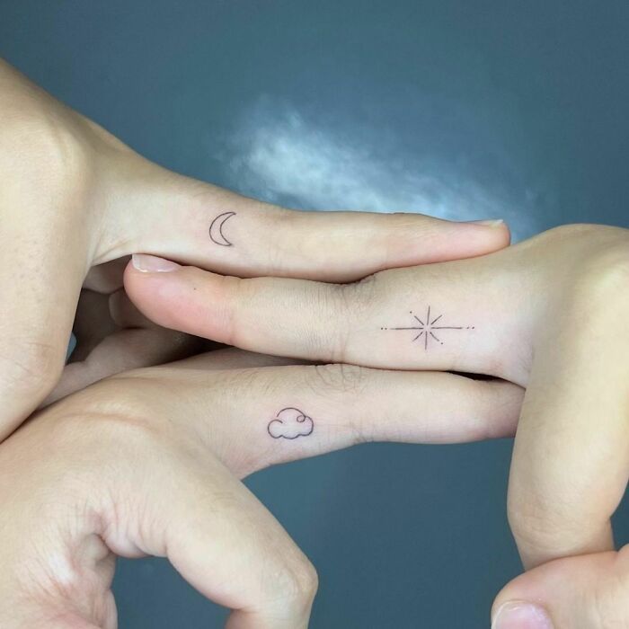 Minimalist best friend tattoos on fingers featuring a moon, star, and cloud design.