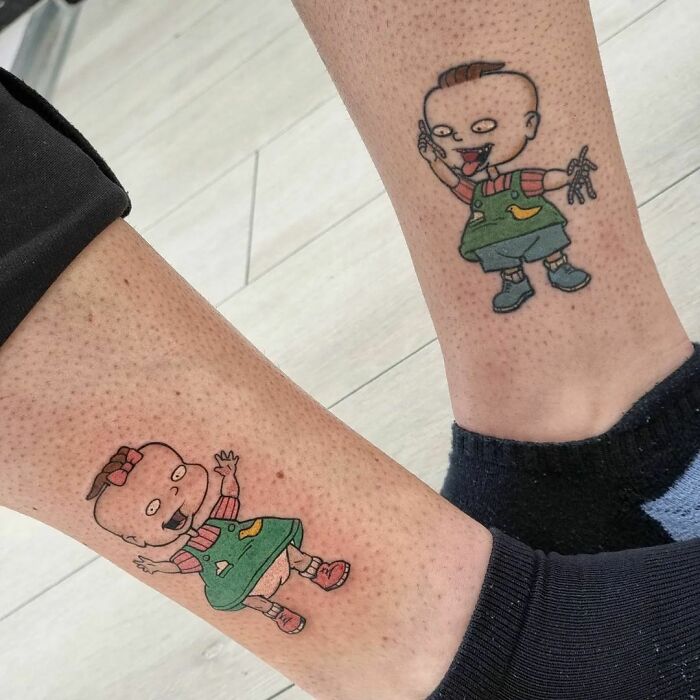 Cartoon tattoos on legs featuring characters Phil And Lil Deville from classic animated shows.