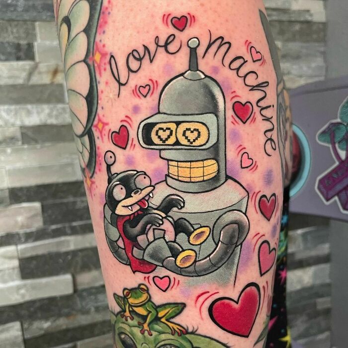 Cartoon tattoo featuring a robot and alien character, surrounded by hearts and the phrase "love machine."