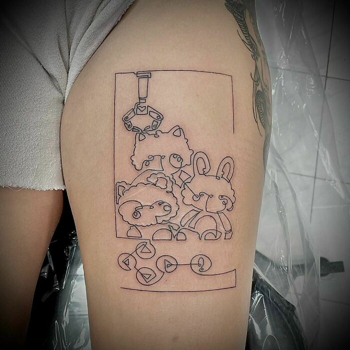 Single-line tattoo of cute animals in a claw machine on a person's thigh.