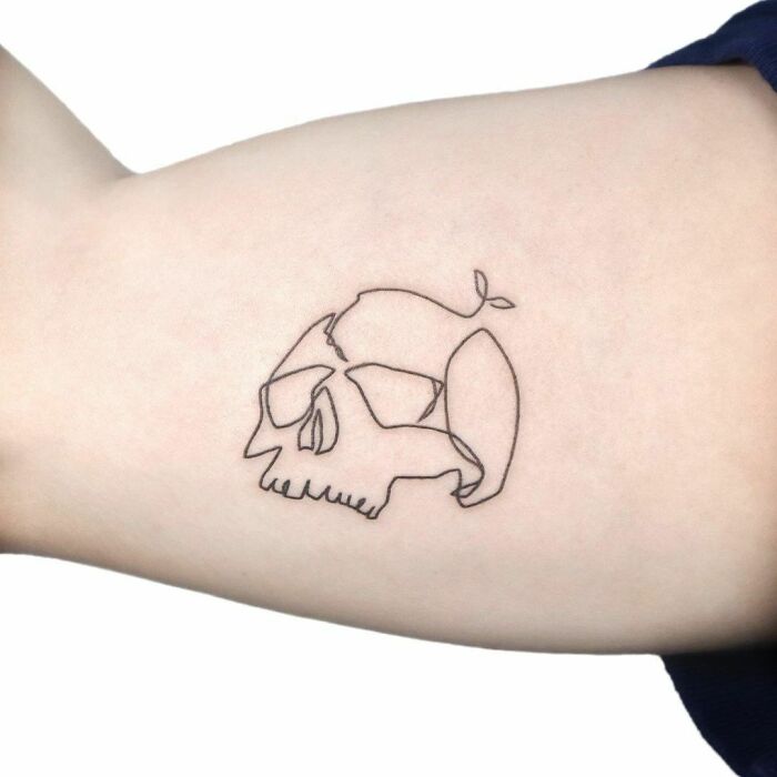 Single-line tattoo of a skull and whale design on forearm, showcasing minimalist artistry.