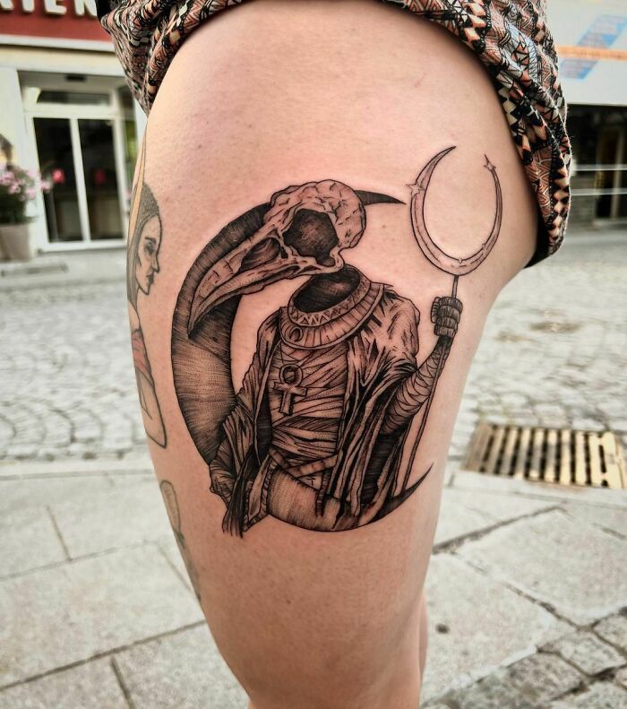 Marvel tattoo featuring an Egyptian-inspired design on a person's thigh, highlighting intricate blackwork details.