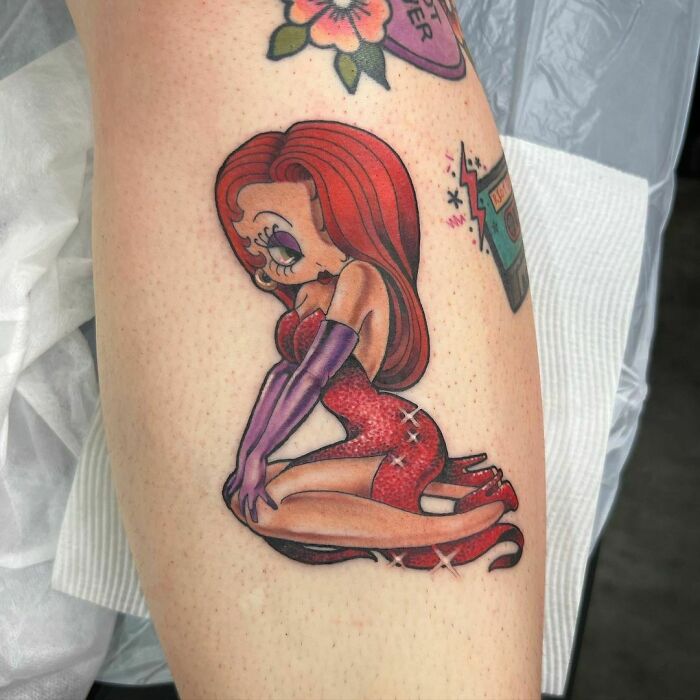 Cartoon tattoo with retro character in a red dress and purple gloves, evoking childhood favorites.