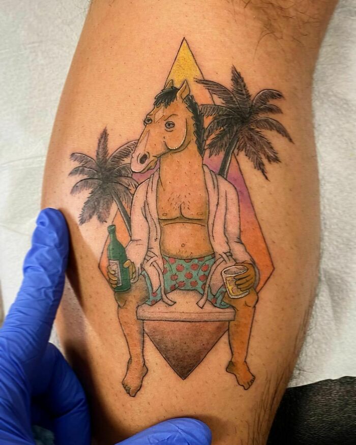 Cartoon tattoo with a horse character lounging in swim trunks, holding drinks, set against tropical palms.