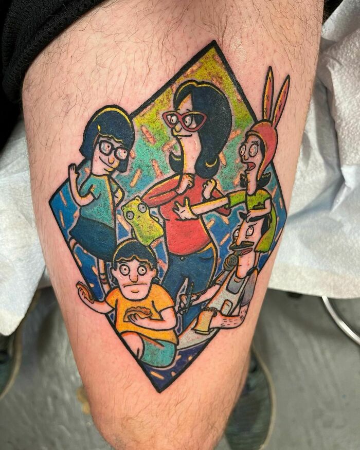 Cartoon tattoo featuring animated family characters in a colorful design on a person's leg.