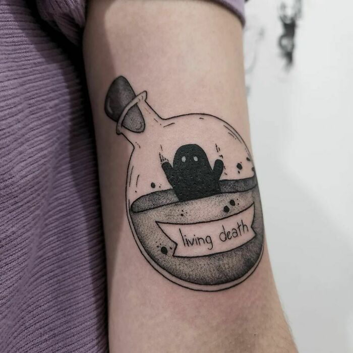 Harry Potter tattoo of a potion bottle with ghostly figure labeled "living death" on an arm.