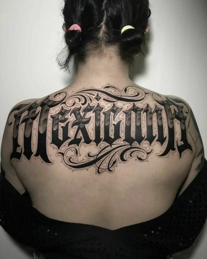 A woman's back with "Mexican" word tattoo featuring intricate blackletter design.