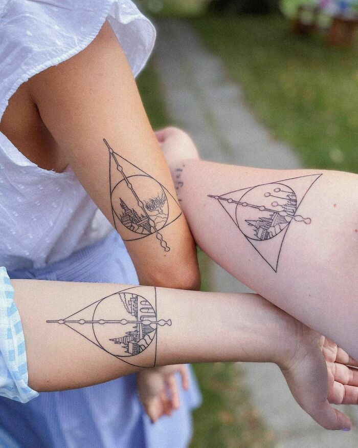 Arms with matching Harry Potter tattoos featuring a triangle and castle design.