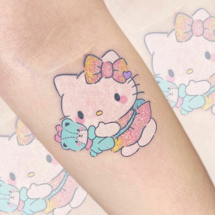 Cartoon tattoo of a cute character holding a small bear, evoking childhood favorites.