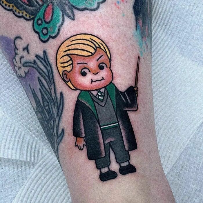 Harry Potter tattoo featuring a character in a green robe holding a wand, showcasing vibrant ink art.