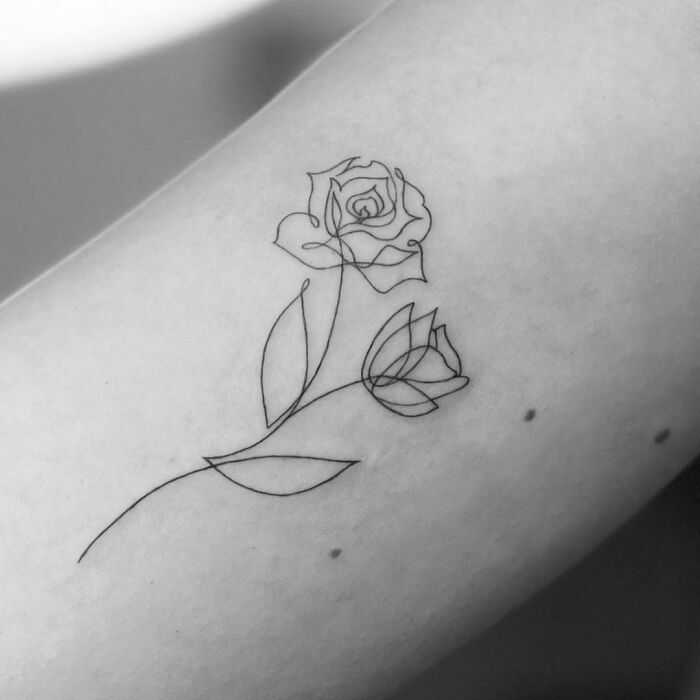 Minimalist line tattoo of a rose on forearm, showcasing elegant and simple line art design.