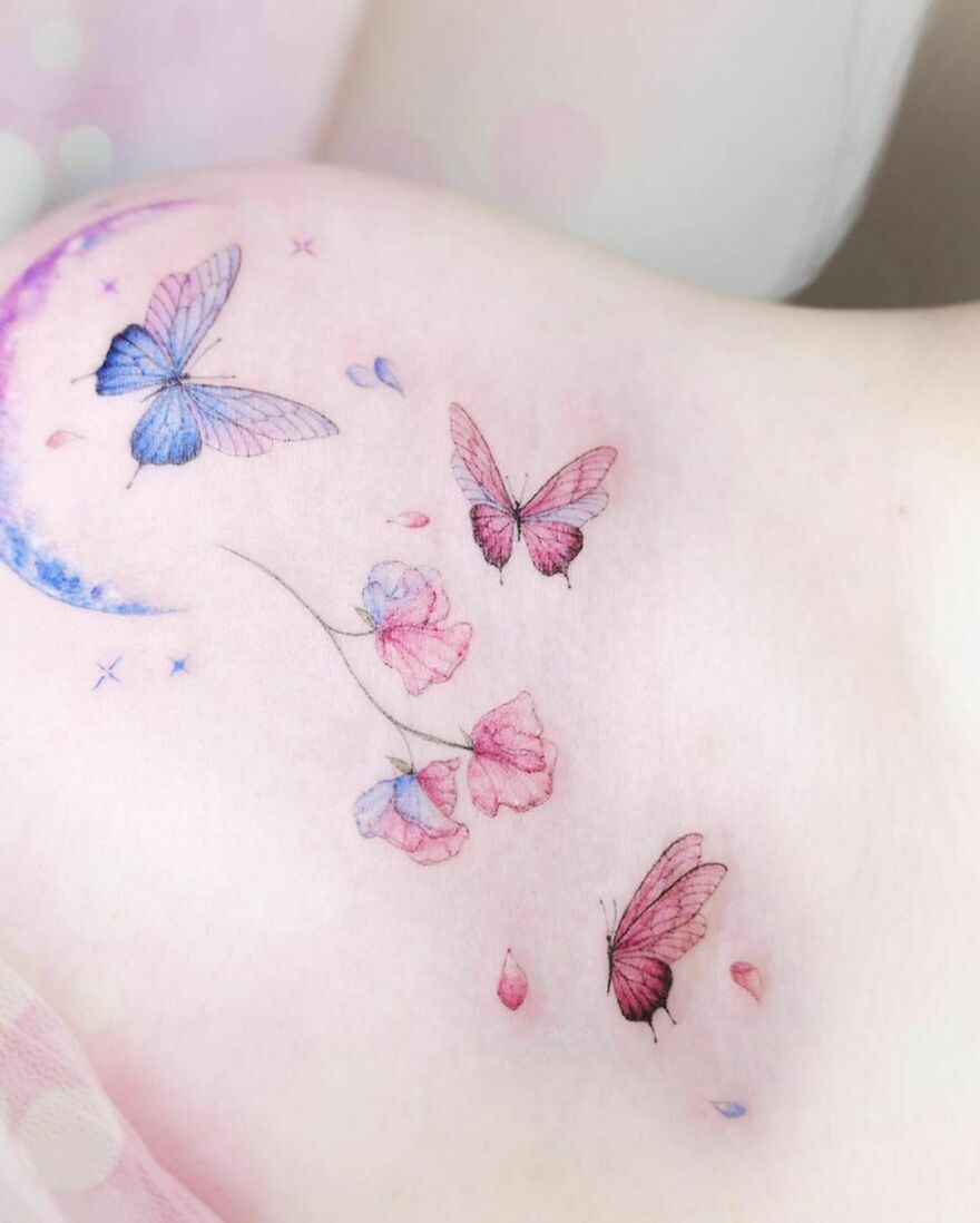Delicate watercolor tattoo featuring butterflies and flowers with pastel colors on light skin.