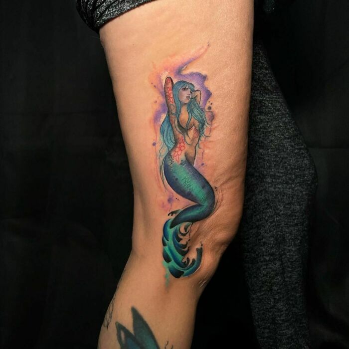 Watercolor tattoo of a vibrant mermaid with blue hair on an arm, showcasing inkspiration.