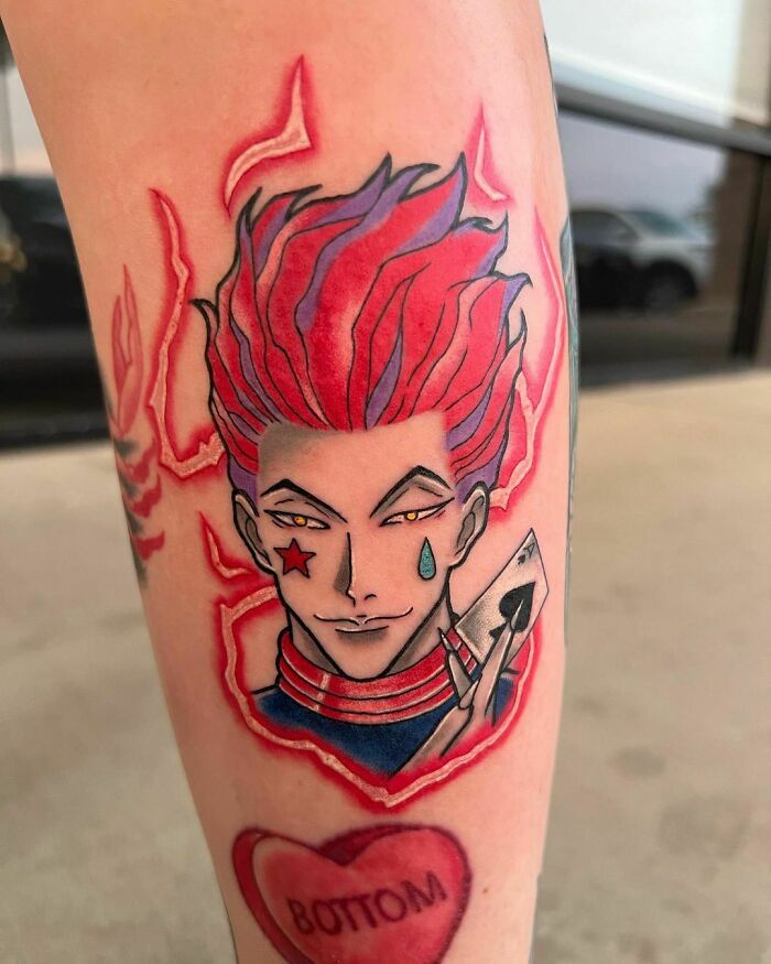 Cartoon tattoo of character with red hair, star, and teardrop face paint, holding a card, inspired by childhood favorites.