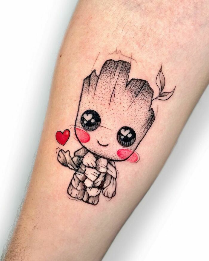 Chibi Groot tattoo with a heart, showcasing Marvel tattoo art on forearm.