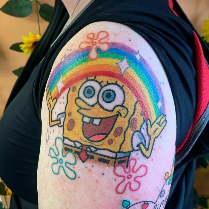 Cartoon tattoo of SpongeBob SquarePants featuring a rainbow on an arm.