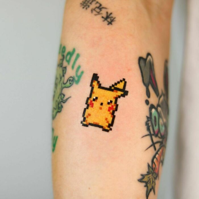 Pixelated Pikachu tattoo on arm, representing cartoon nostalgia.